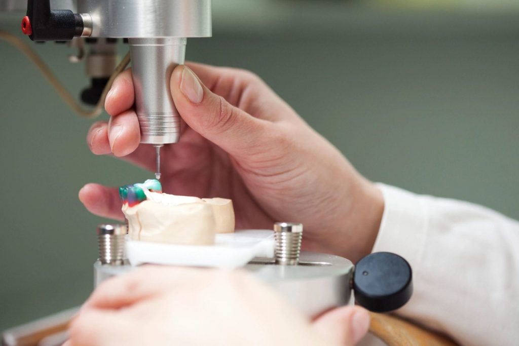 A dentist using some machinery to create veneers.
